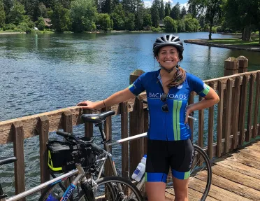 Guest posing on wooden bridge, lake or river in background.