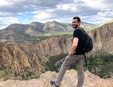 Guest standing on cliff's edge overlooking Smith Rock Park.