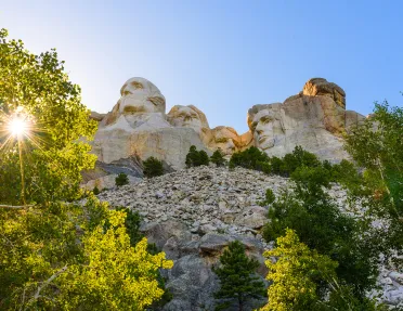 Sun shining on Mount Rushmore and trees