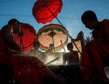 novice monks beating a new dry with palm reeds and splashing water