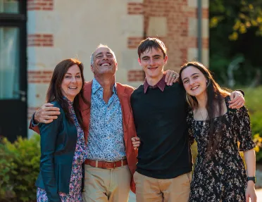 Four guests all embracing, brick building behind them.
