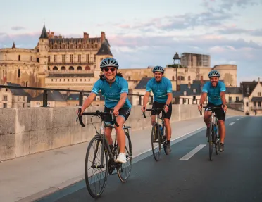 Three guests cycling in French town, Château Royal d'Amboise in background.