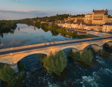 Bird's eye shot of cyclists over Loire River during sunset.  Château Royal d'Amboise behind.