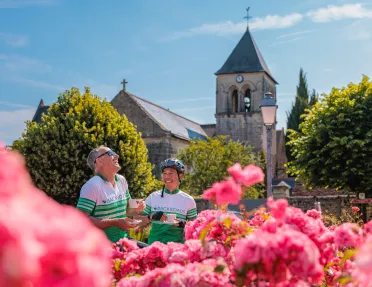 Two guests in flower garden, church behind them.