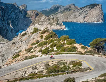 Biker riding around a bend on the coast of Mallorca.