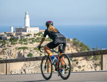 Biker riding on a road along Mallorca coast, with church tower in Background.
