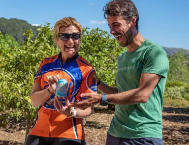 Two bikers posing with a can of wine in a vineyard.