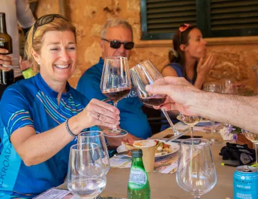 People saying cheers with glasses of red wine.