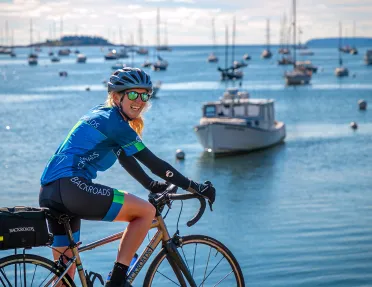 Guest biking with ocean and ships in background.