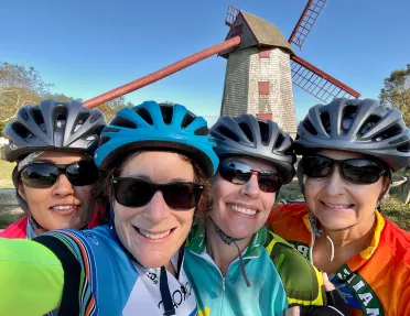 Group of four guests in glasses, windmill behind them.