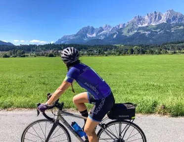 Backroads biker riding on road with Tyrolean Alps in background.