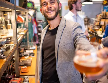 Person offering camera a glass of beer.