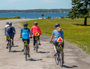 Five guests riding along a coastal trail, ocean to their left.