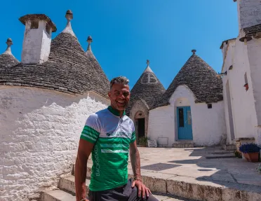 Guest smiling in front of Alberobello houses.