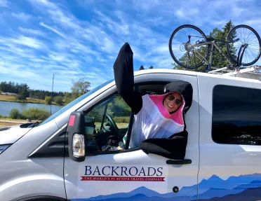 Leader in orca costume waving to camera in the front seat of BR van.