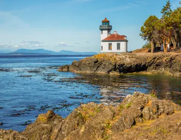 Coastal shot of a small lighthouse on a rocky shore.