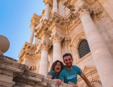 People smiling down from outside a church in Sicily