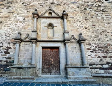 Shot of stone crafted entryway, engraved door at center.