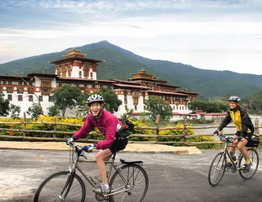 Two bikers riding beside a temple in Bhutan