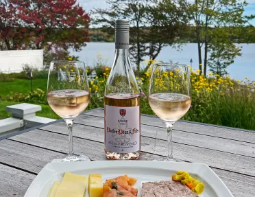 Shot of rose wine, platter of food, lox, cheese, meat, etc.