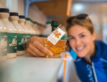Guest holding maple syrup bottle to camera.