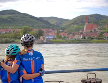 Adult and child posing together at boat deck overlooking Danube River.
