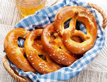 Lager beer mug and fresh baked homemade pretzel with sea salt on wooden table. Classic beer snack