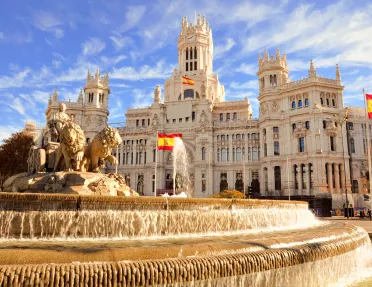 Shot of the Plaza de Cibeles, Spanish flags flying around it.