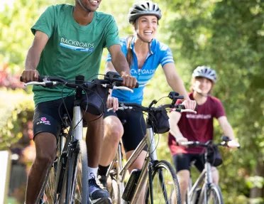 Three guests biking towards camera, all smiling.