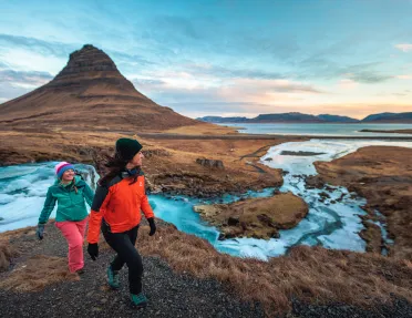 Two hikers walking along side stream of water in Iceland.