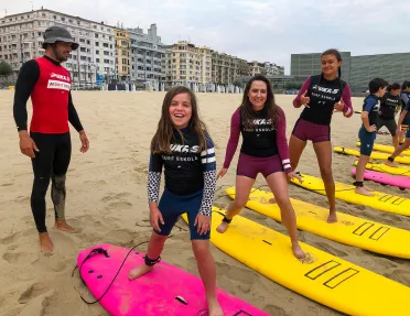 Group of young guests at surf lesson, instructor behind them.