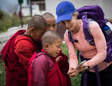 Woman showing her phone to young monks in Bhutan