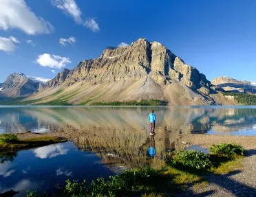 Wide shot of large lake, guest looking towards craggy mountains.