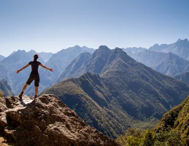 Guest on mountaintop overlooking sharp, craggy mountains.