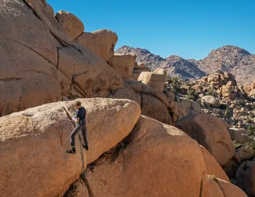 Guest rock climbing with desert vista behind them.