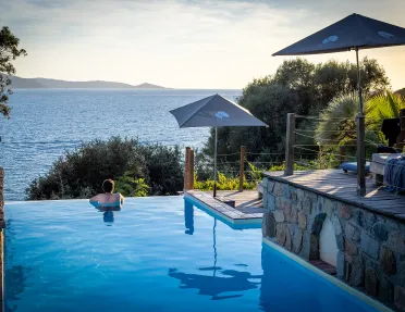 Guest relaxing in a pool, overlooking ocean and distant hills.