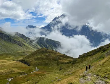 Wide shot of mountainous vista, two guests in distance.