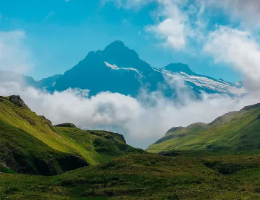 Valley view of Alpine mountains and clouds at the base.