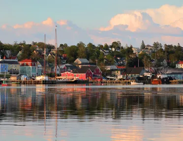 Wide shot of seaside town at sunset, vibrant red houses scattered throughout.