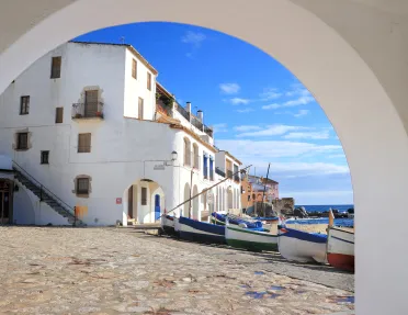 Archway shot of white coastal houses, boats, ocean. 
