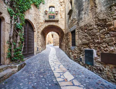 POV shot of stone alleyway, doors, windows, arches.