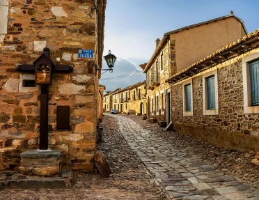 Alleyway shot of stone-built town, windows, doors dot the alley.