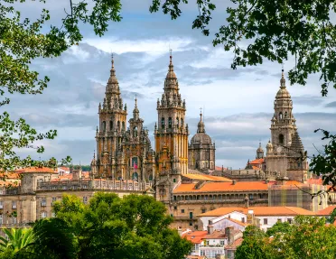 POV shot of Cathedral of Santiago de Compostela, taken from distant treeline.