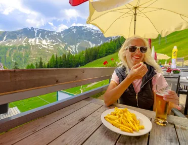 Woman eating french fries on restaurant patio.