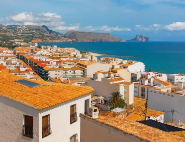 Shot of coastal town, white and tan houses, ocean.