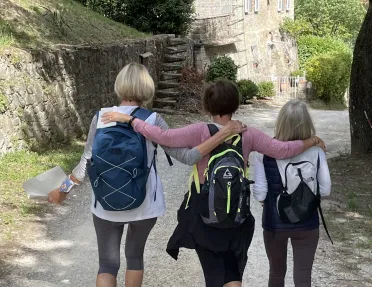 Three guests walking down Italian road, small stone shack in distance.