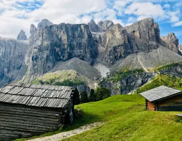 Shot of two old, wooden houses, angular cliffs in distance.