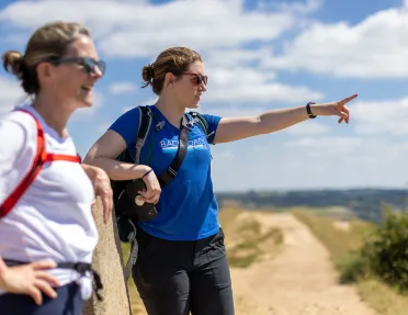 Two hikers on trail, pointing at view in the distance.