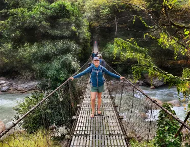 Hiker standing on a bridge over a river in Nepal