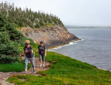 Two guests walking alongside coastal cliff.